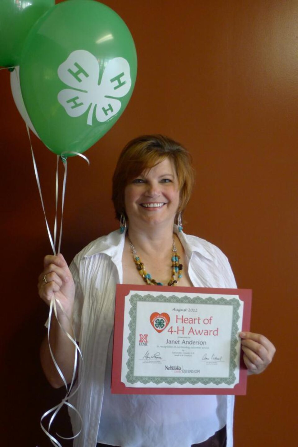 Janet Anderson holding 4-H balloons and a certificate. 