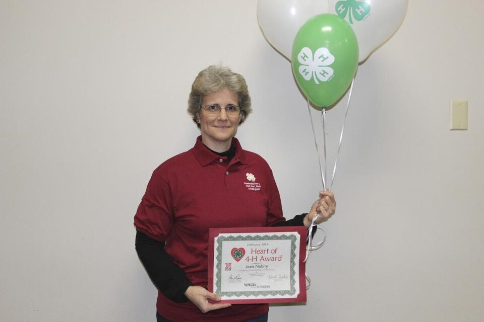 Jean Nabity holding 4-H balloons and a certificate. 