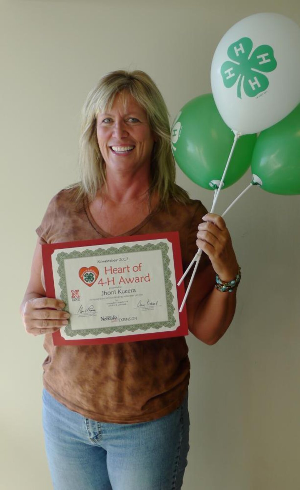 Jhoni Kucera holding 4-H balloons and a certificate. 