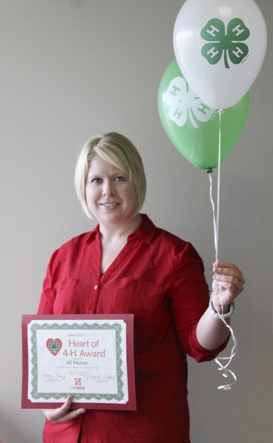 Jill Hattan holding 4-H balloons and a certificate. 