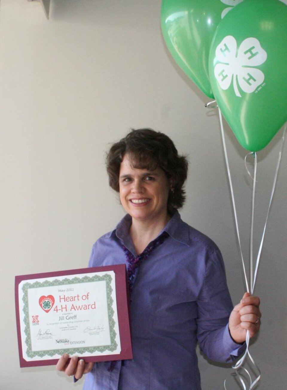 Jill Greff holding 4-H balloons and a certificate. 