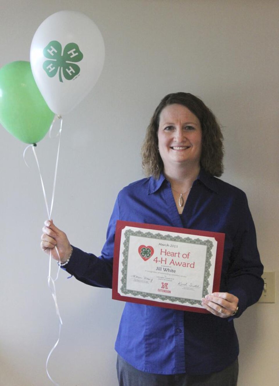 Jill White holding 4-H balloons and a certificate. 