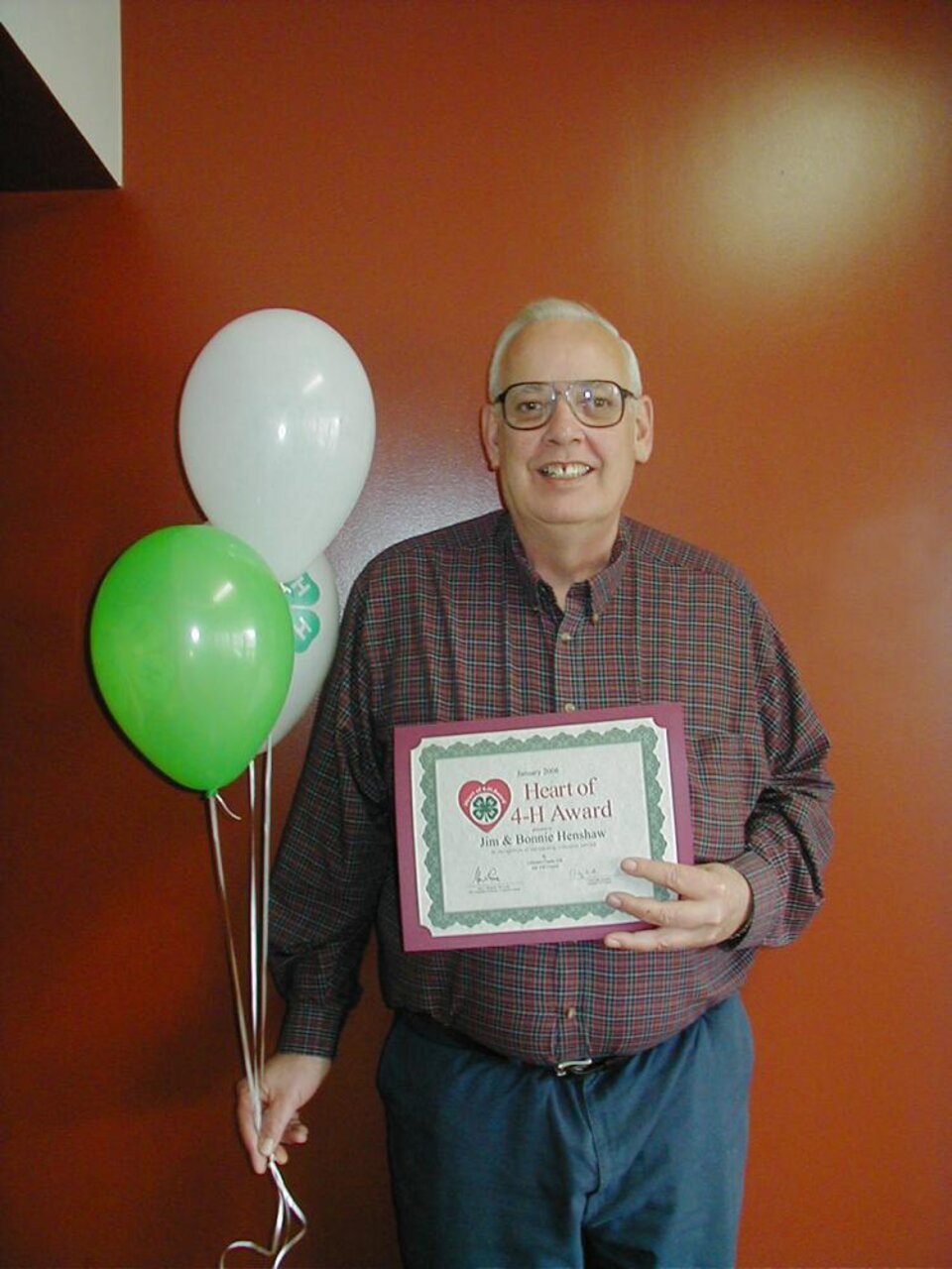 Jim Henshaw holding balloons and a certificate 