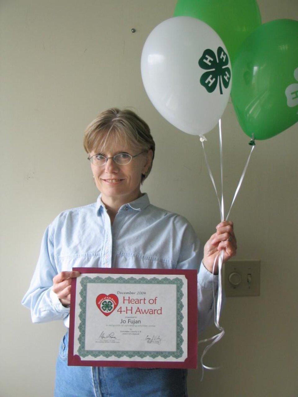 Jo Fujan holding balloons and a certificate 