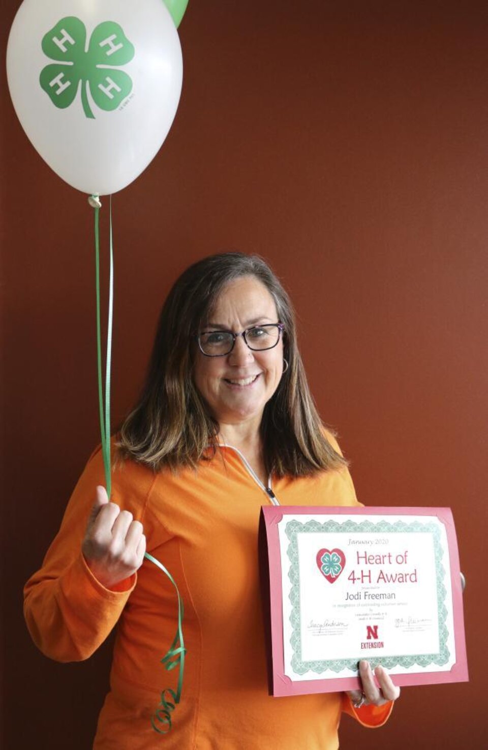 Jodi Freeman holding 4-H balloons and a certificate. 