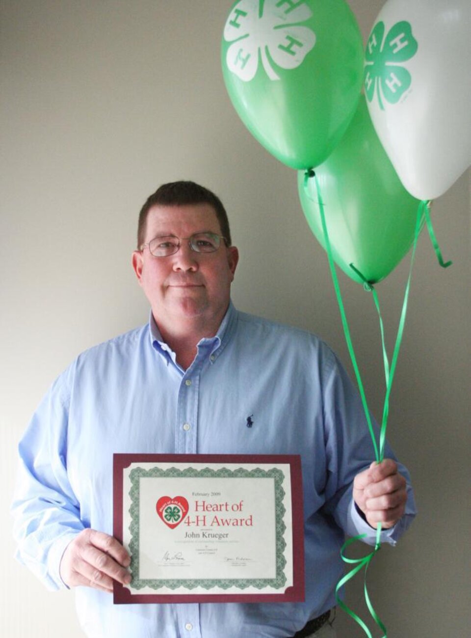 John Krueger holding balloons and a certificate 