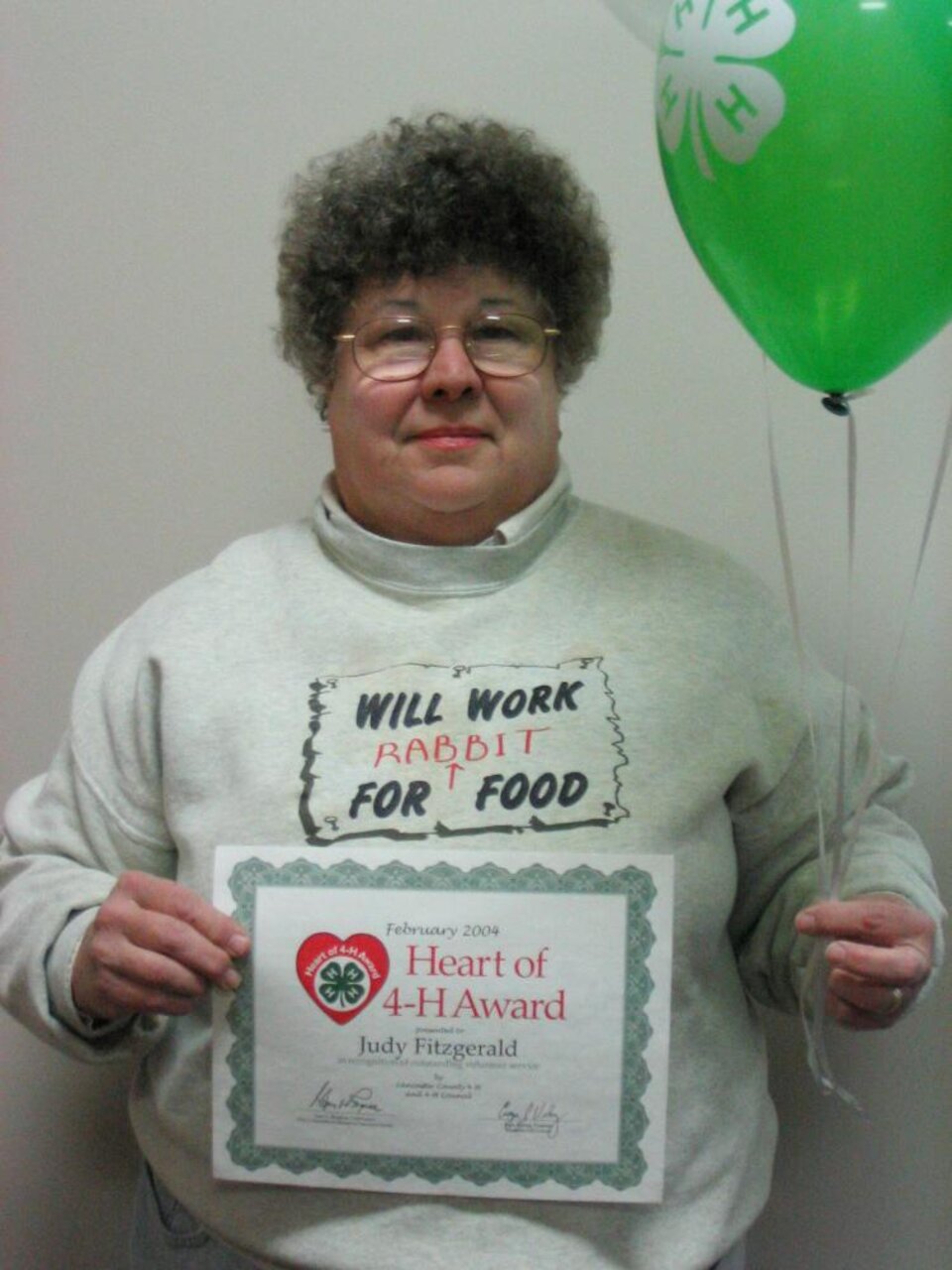 Judy Fitzgerald holding balloons and a certificate 