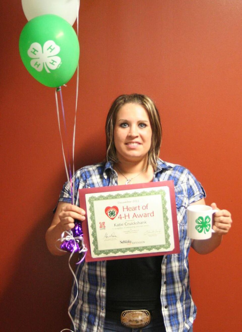 Katie Cruickshank holding 4-H balloons and a certificate. 