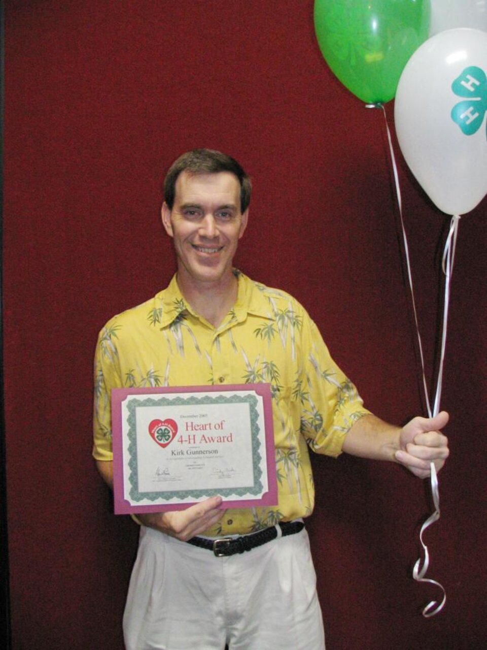 Kirk Gunnerson holding balloons and a certificate 