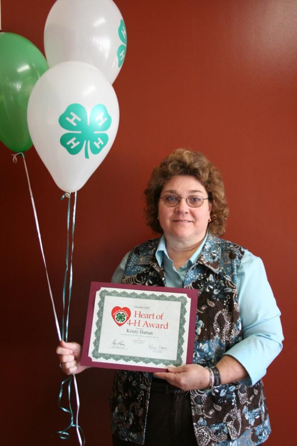 Kristy Hattan holding balloons and a certificate 