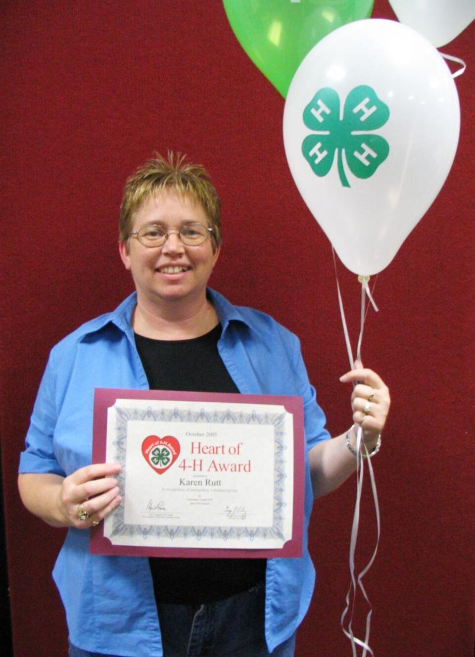 Karen Rutt holding balloons and a certificate 