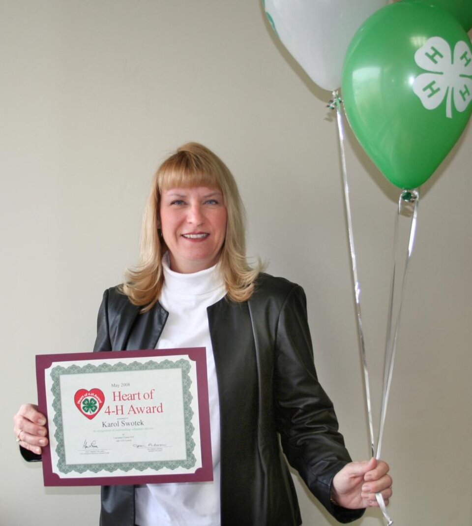 Karol Swotek holding balloons and a certificate 