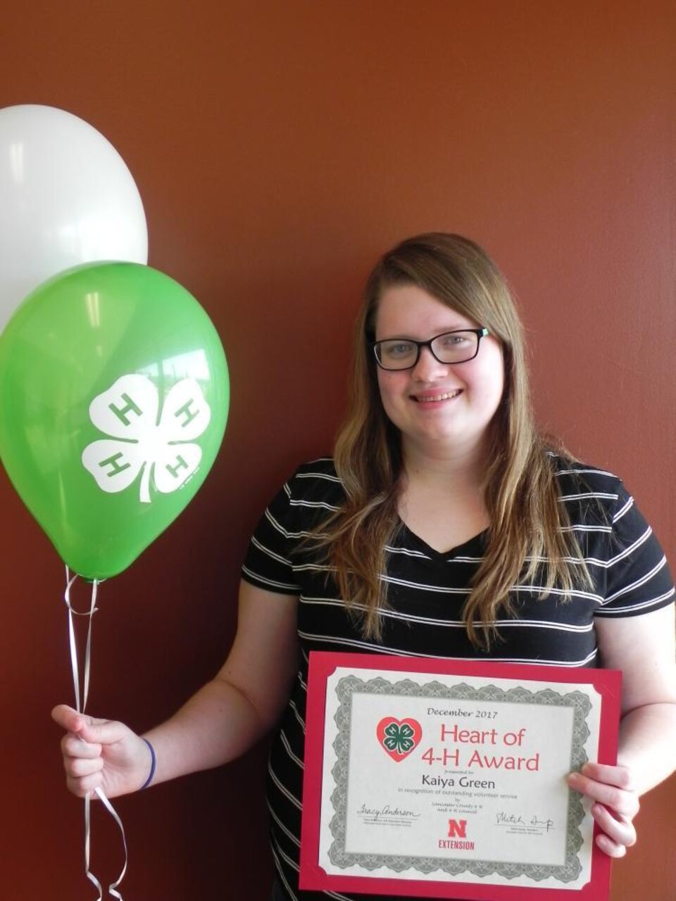 Kaiya Green holding 4-H balloons and a certificate. 