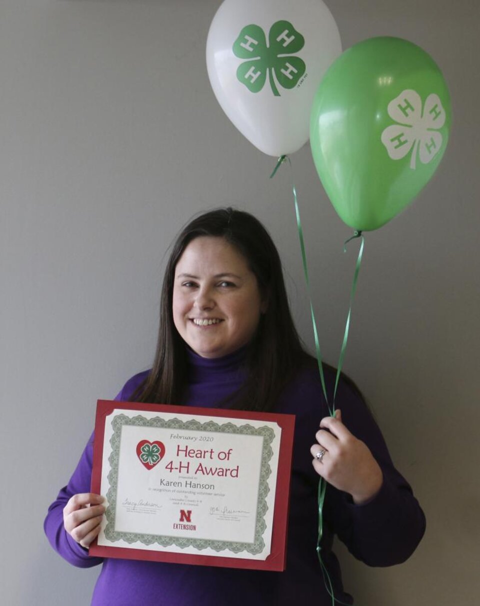 Karen Hanson holding 4-H balloons and a certificate. 