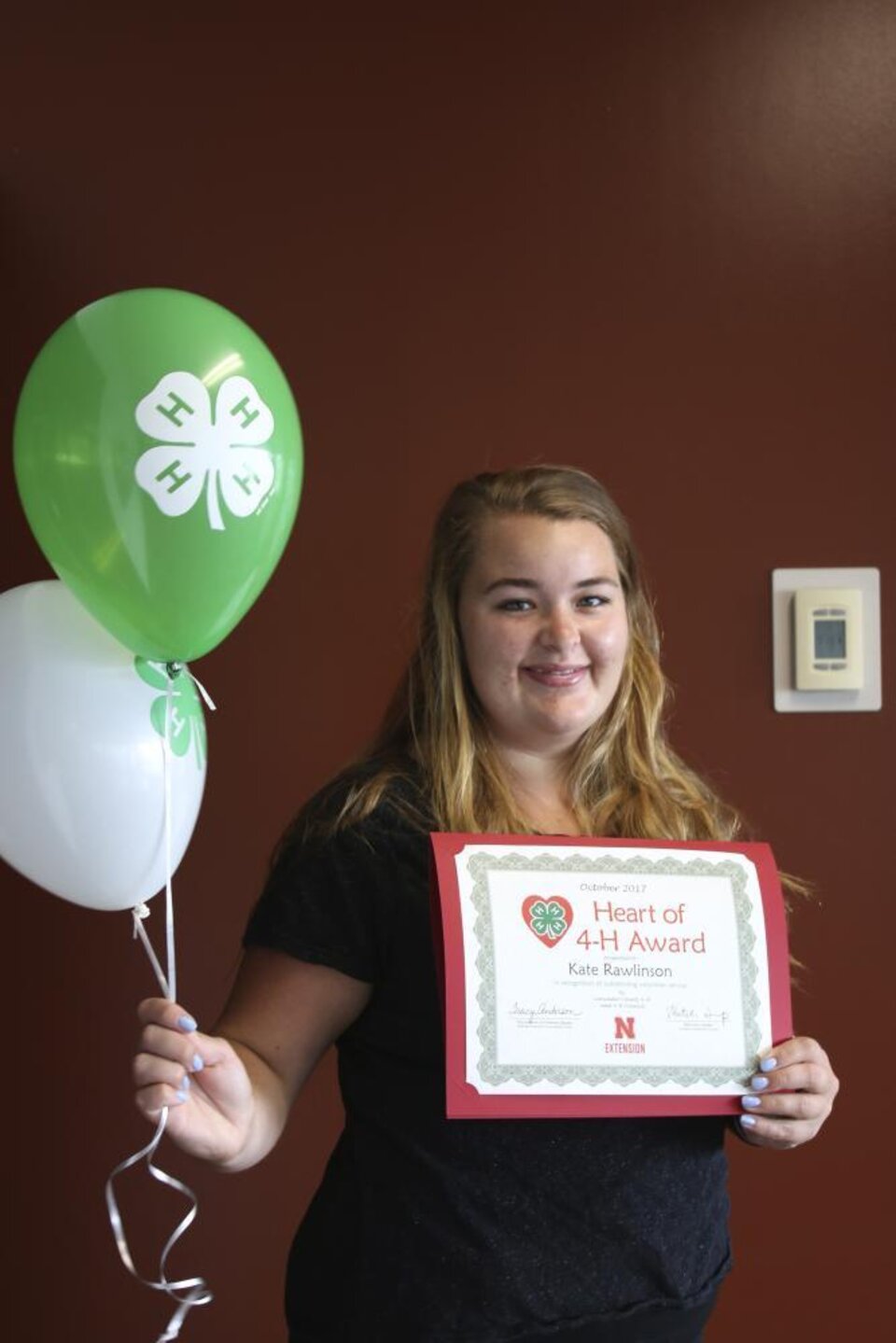 Kate Rawlinson holding 4-H balloons and a certificate. 