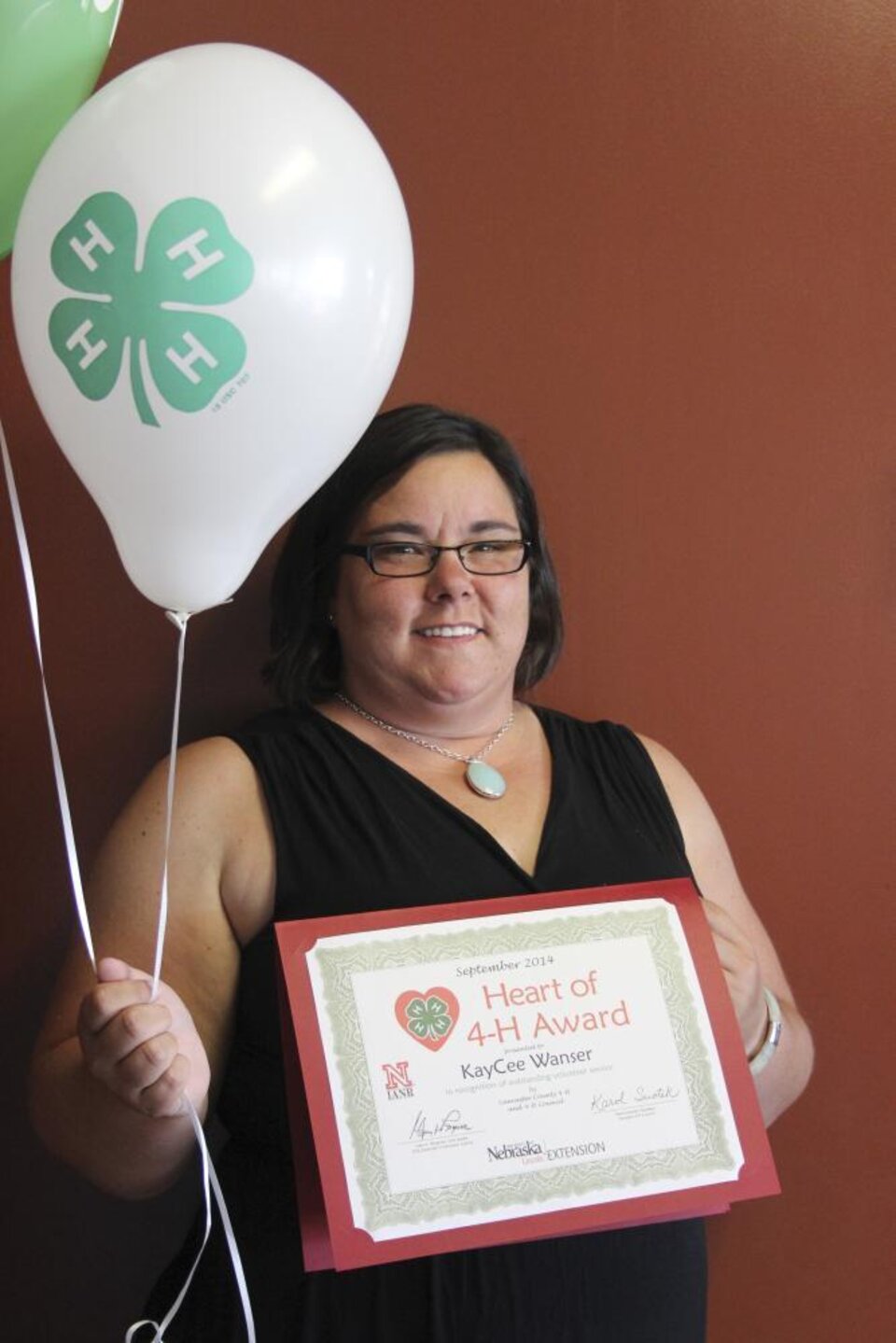 KayCee Wanser holding 4-H balloons and a certificate. 