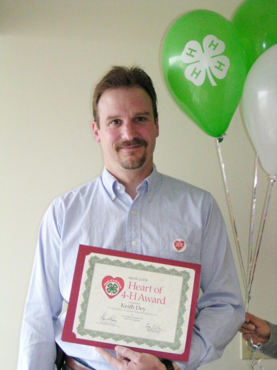 Keith Dey holding balloons and a certificate 