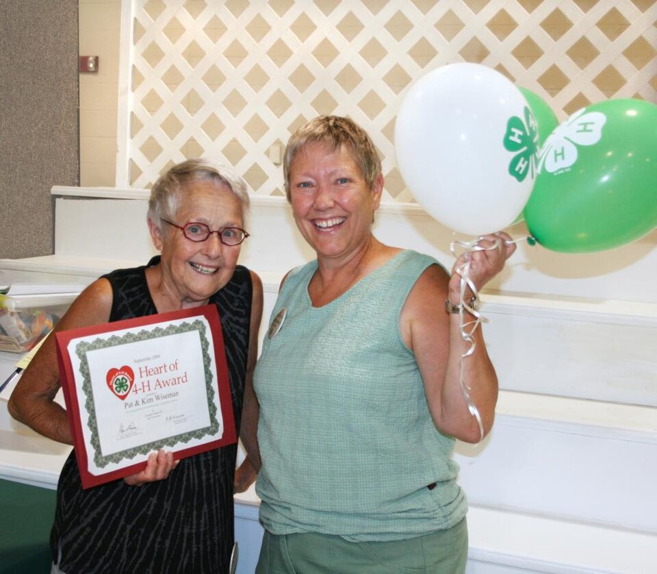 Pat and Kim Wiseman standing together and holding balloons and a certificate 