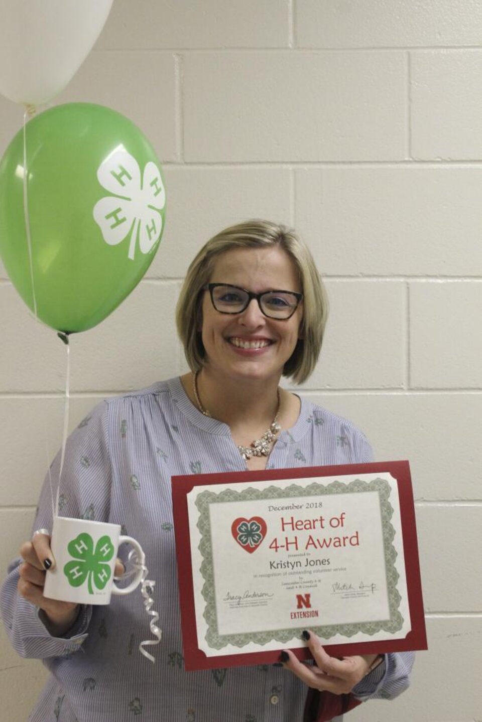 Kristyn Jones holding 4-H balloons and a certificate. 