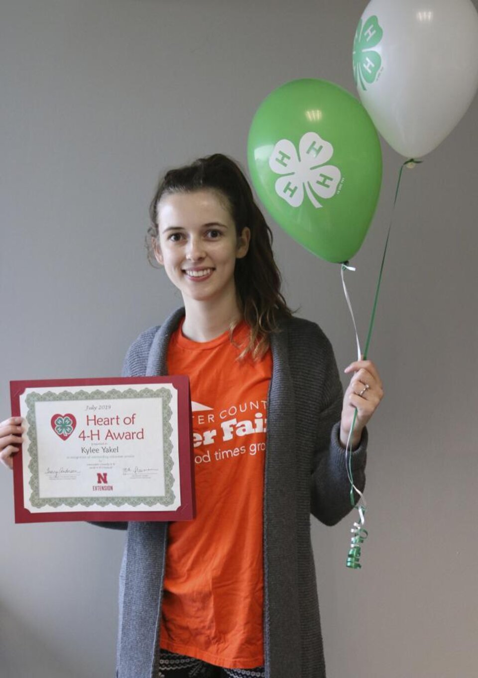 Kylee Yakel holding 4-H balloons, and a certificate. 