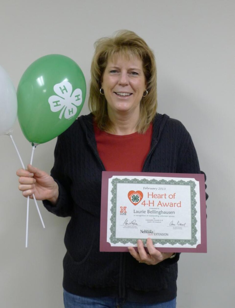 Laurie Bellinghausen holding a 4-H balloon and certificate. 