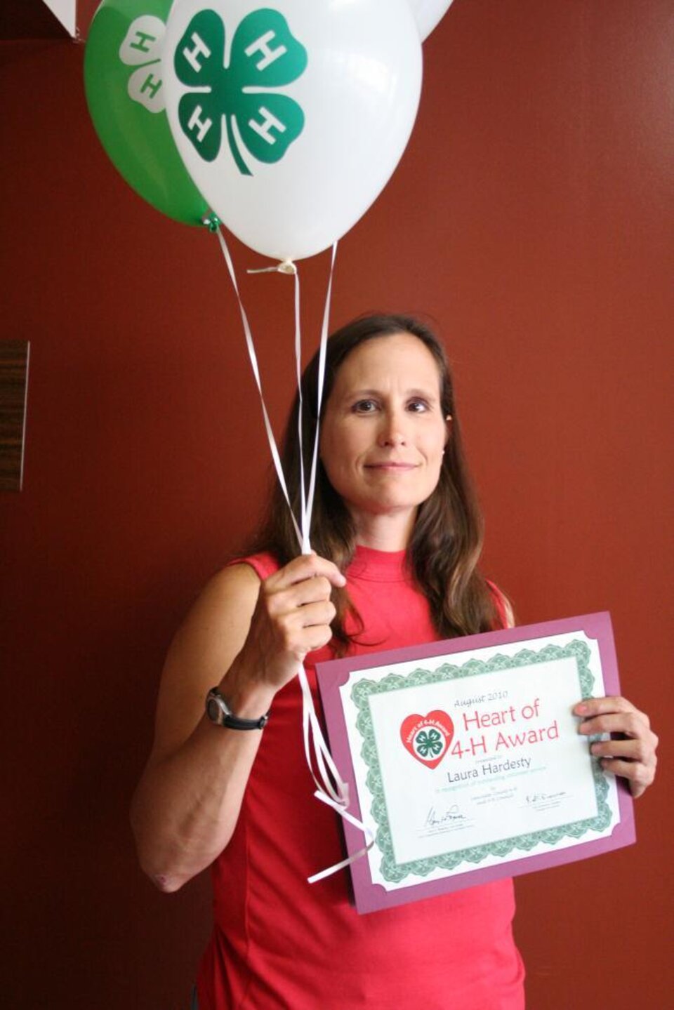 Laura Hardesty holding 4-H balloons and a certificate. 