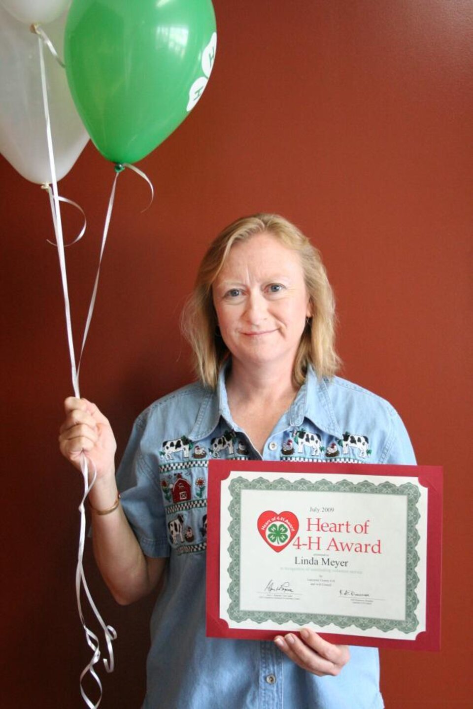 Linda Meyer holding balloons and a certificate 