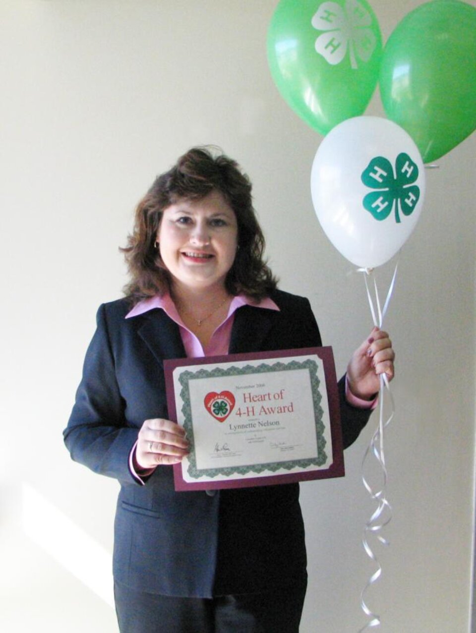 Lynnette Nelson holding balloons and a certificate 