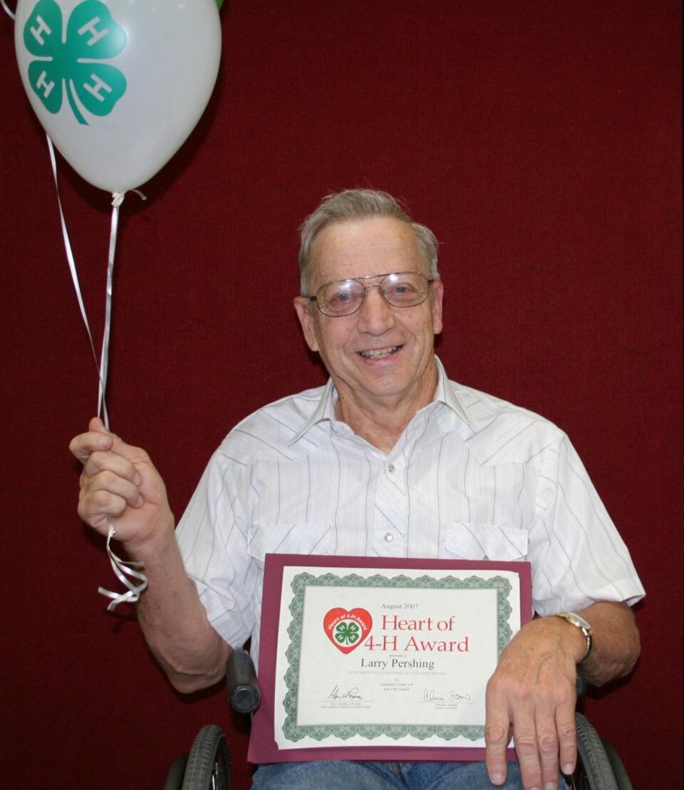 Larry Pershing holding balloons and a certificate 