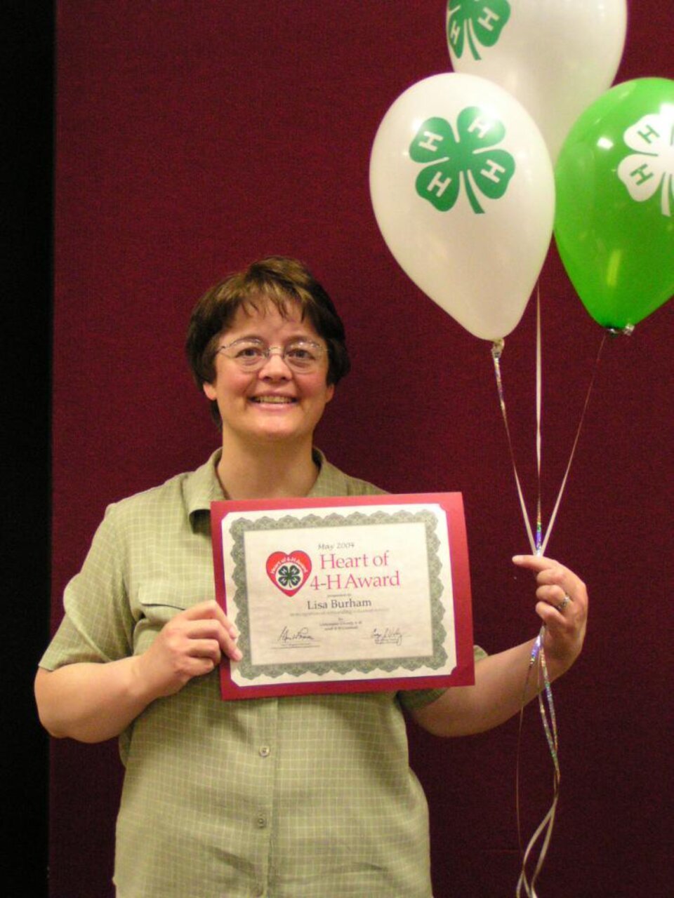 Lisa Burham holding balloons and a certificate 