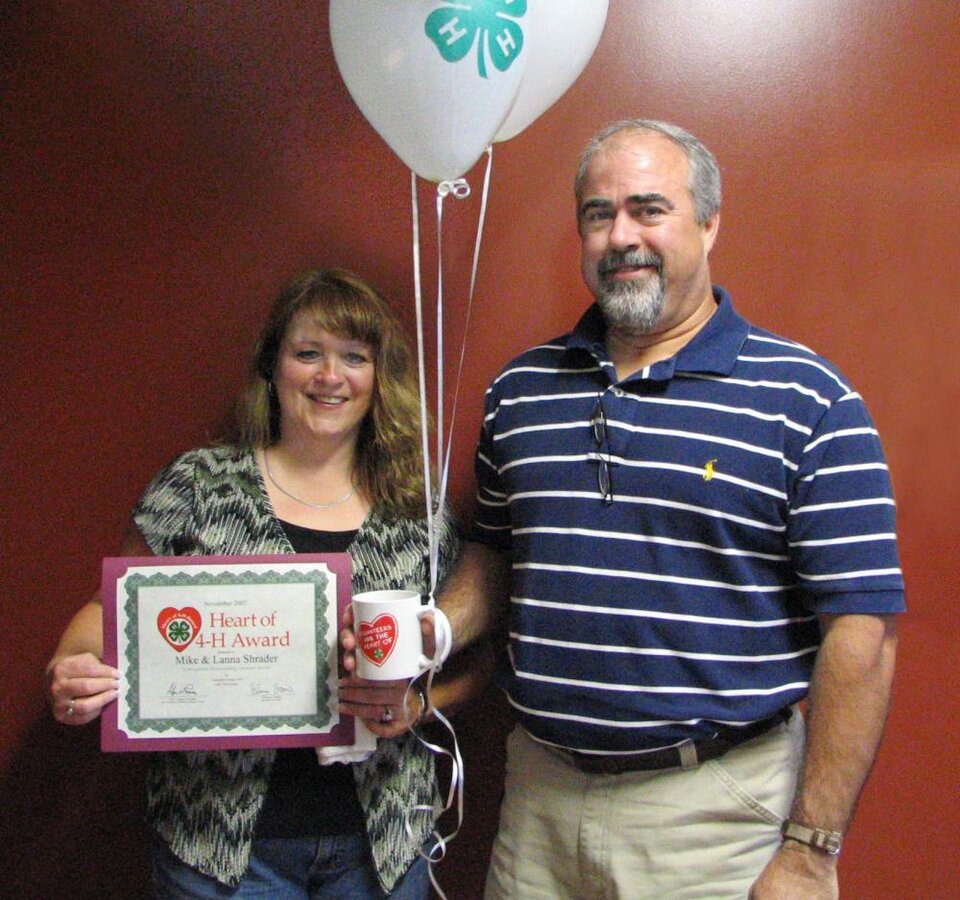 Mike and Lanna Shrader standing together and holding balloons and a certificate 