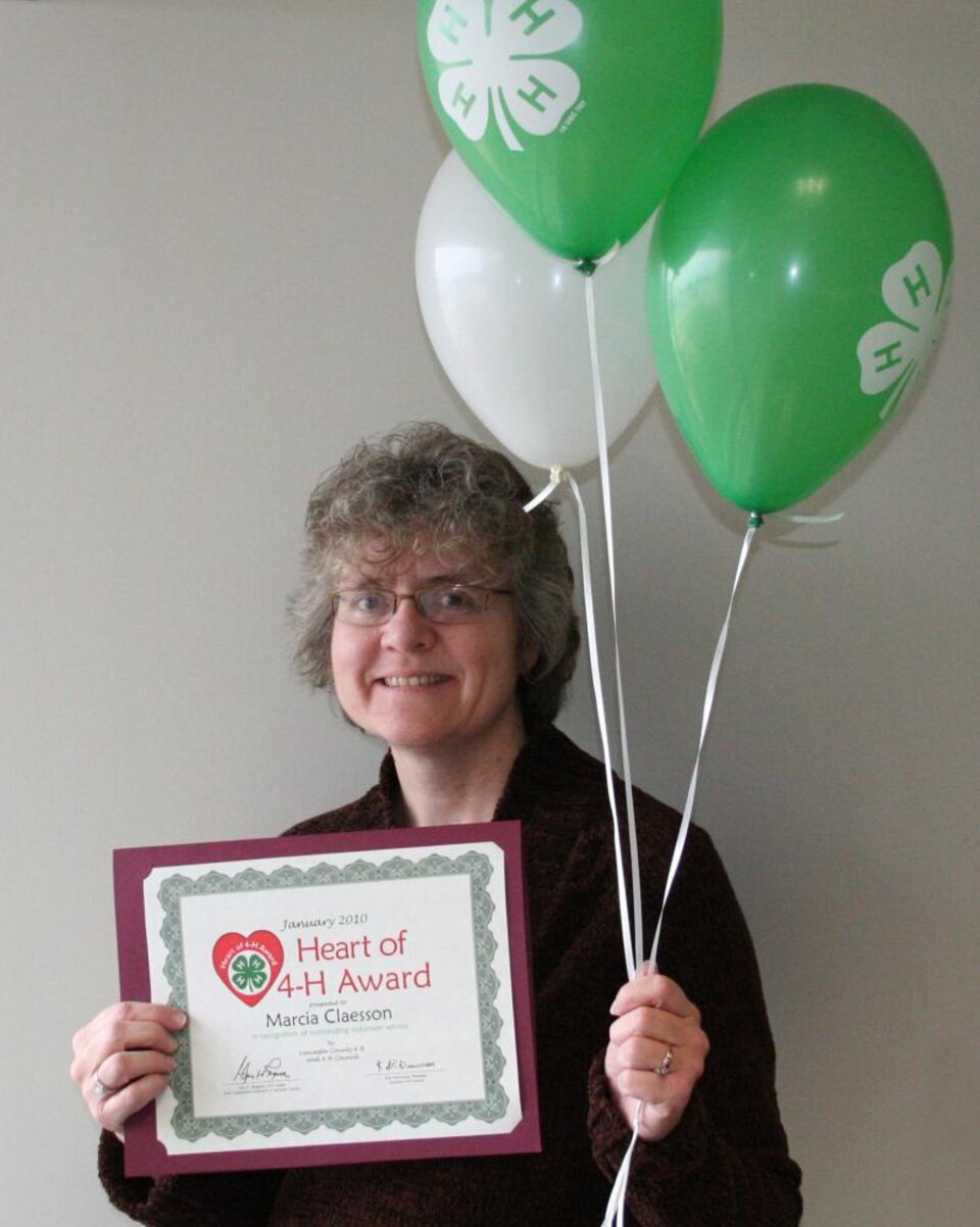 Marcia Claesson holding balloons and a certificate. 