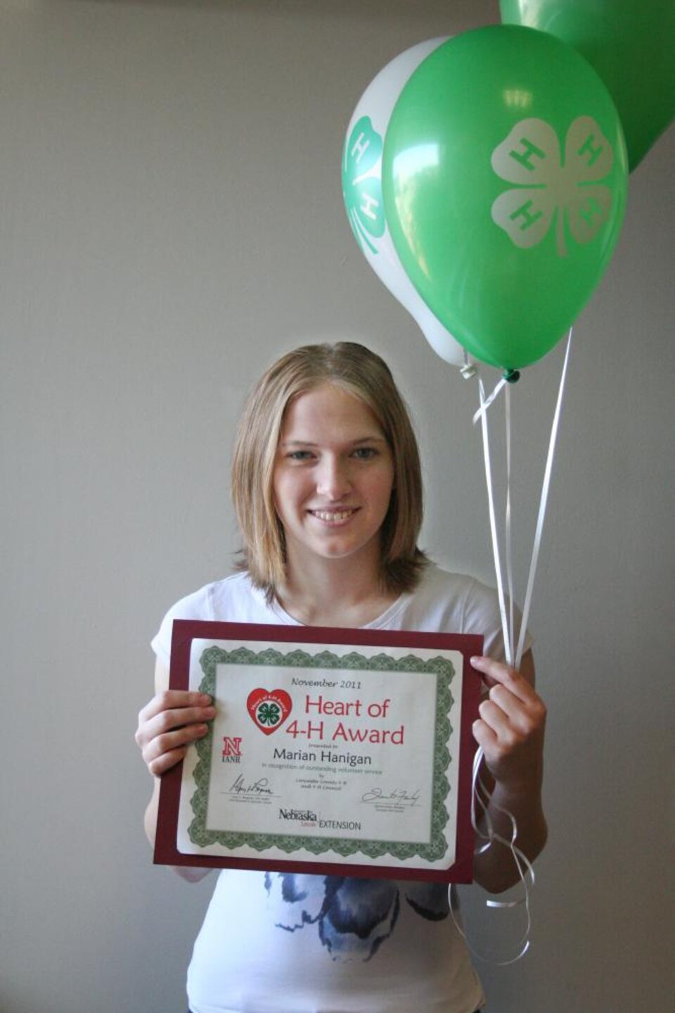 Marian Hanigan holding 4-H balloons and a certificate. 