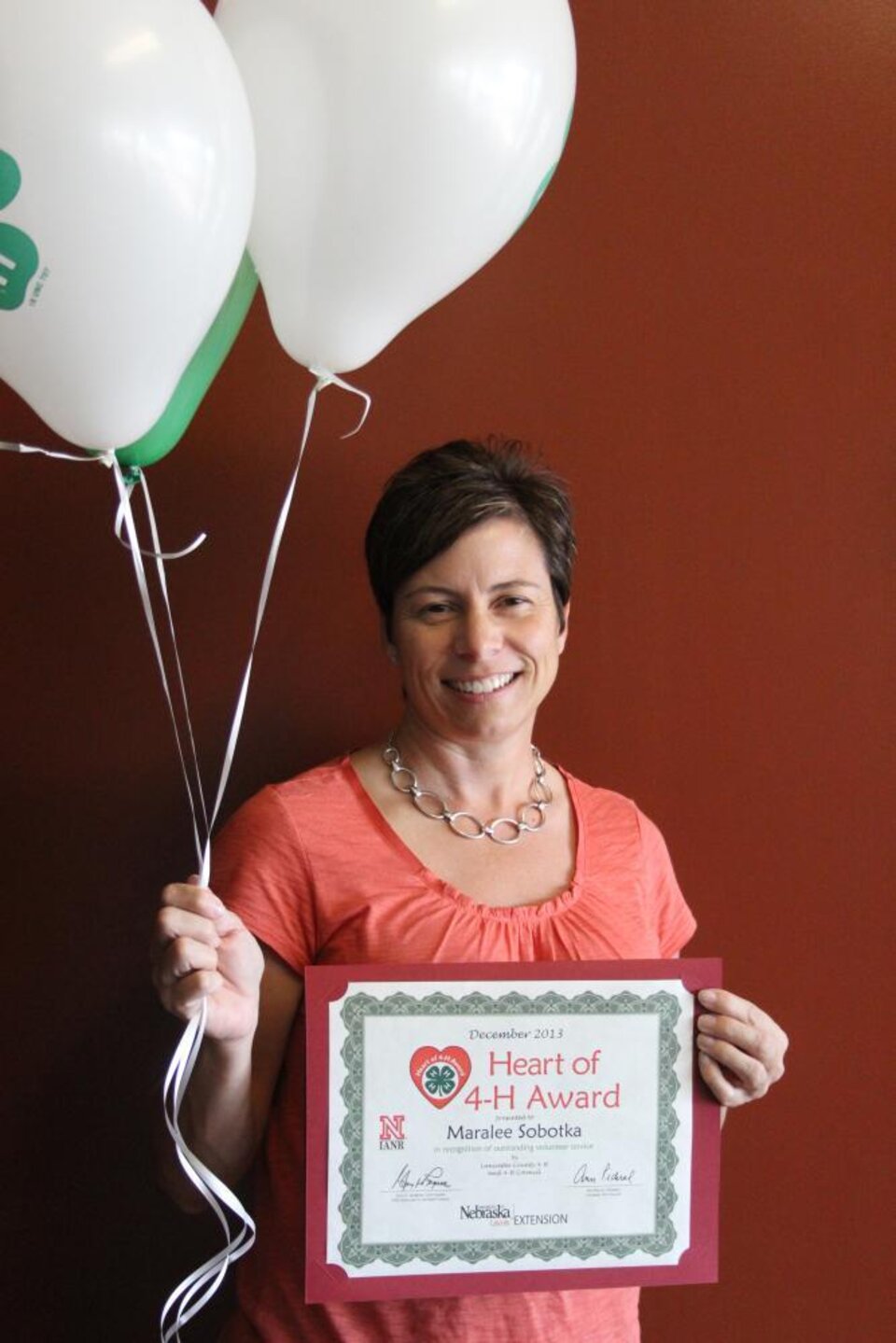 Maralee Sobotka holding 4-H balloons and a certificate. 