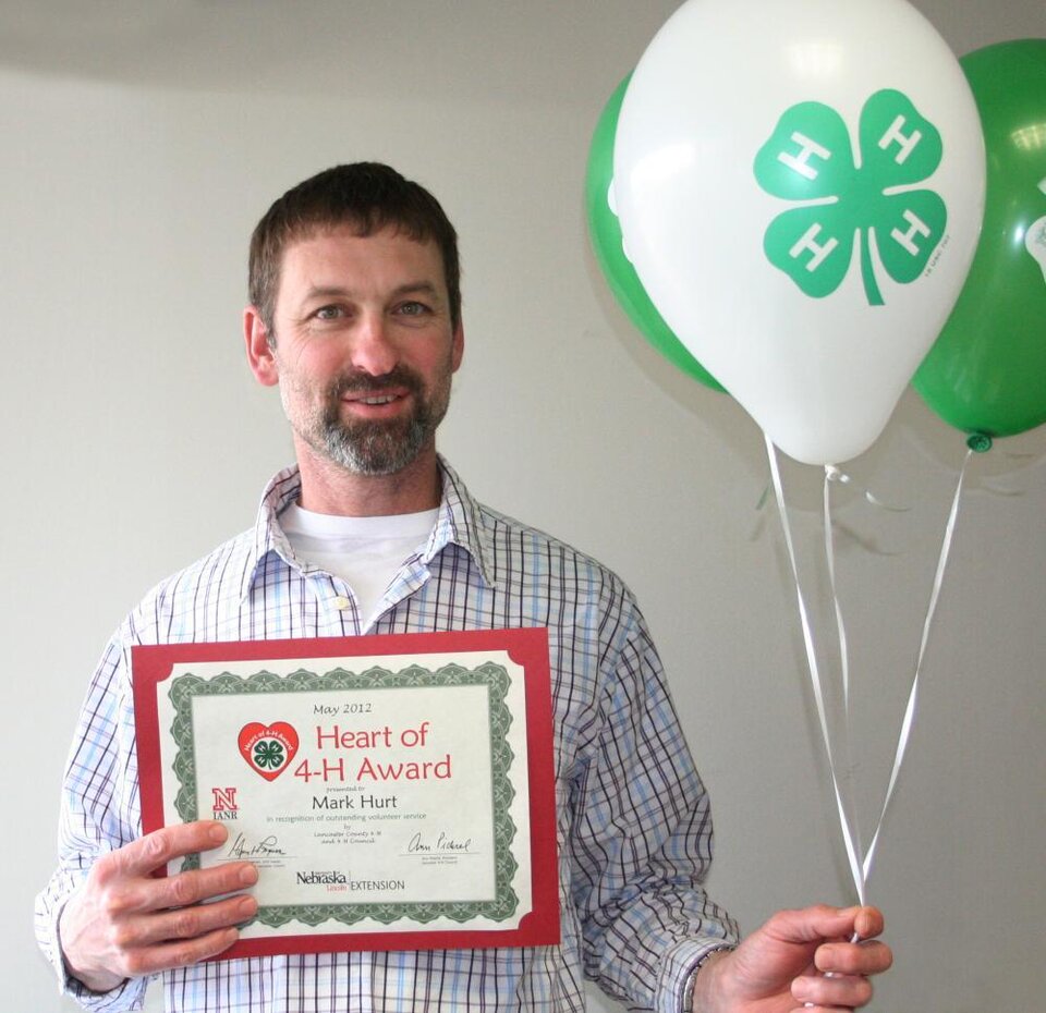 Mark Hurt holding 4-H balloons and a certificate. 