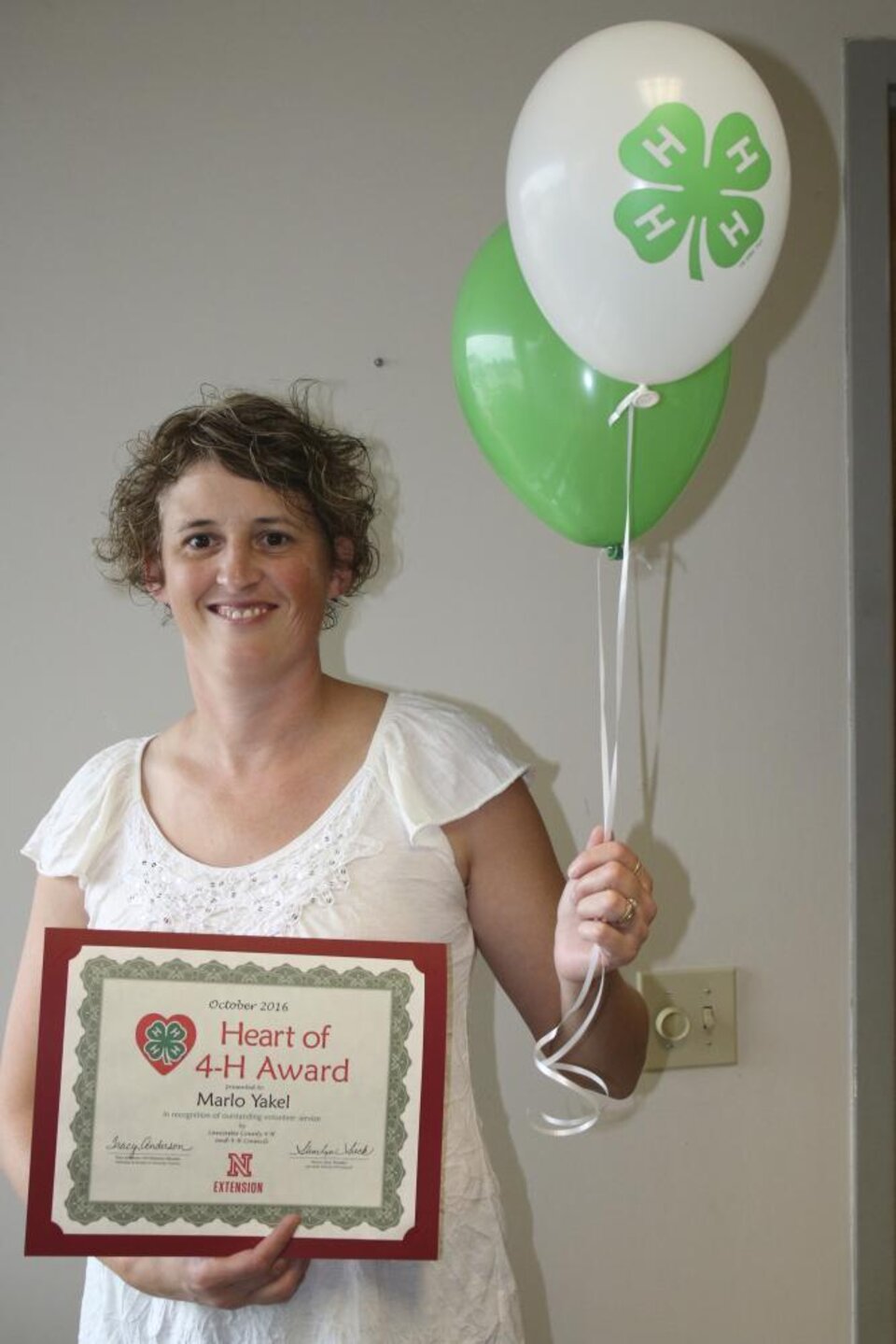 Marlo Yakel holding 4-H balloons and a certificate. 