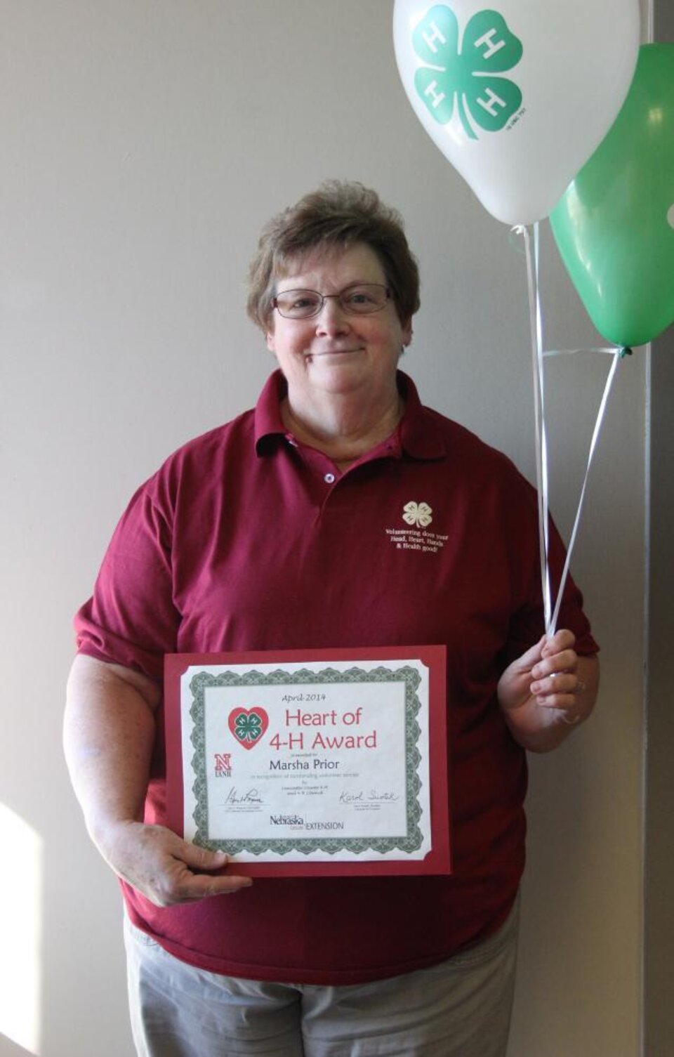 Marsha Prior holding 4-H balloons and a certificate. 