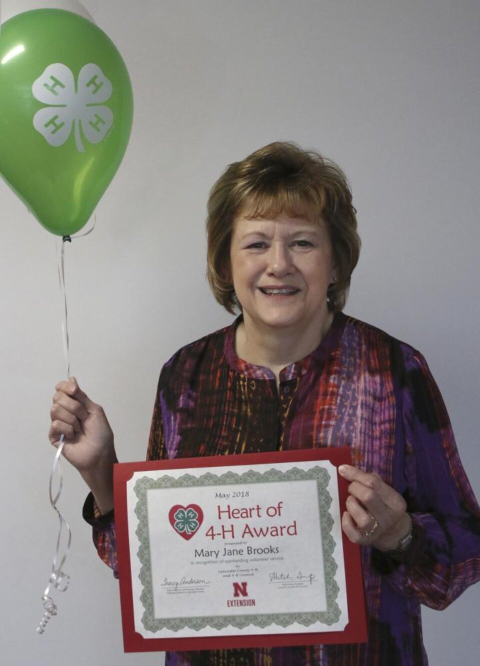 Mary Brooks holding 4-H balloons and a certificate. 