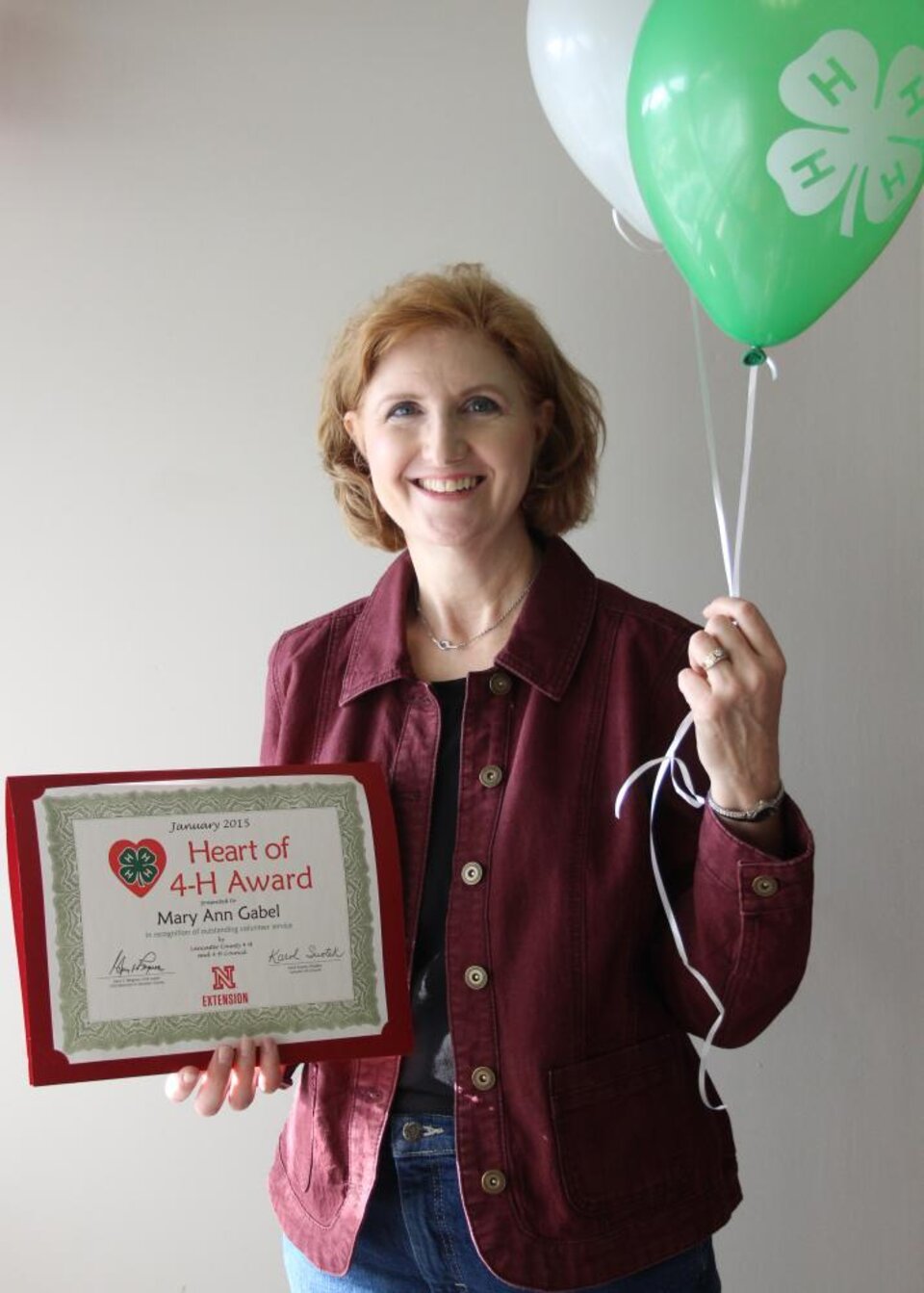 Mary Ann Gabel holding 4-H balloons and a certificate. 