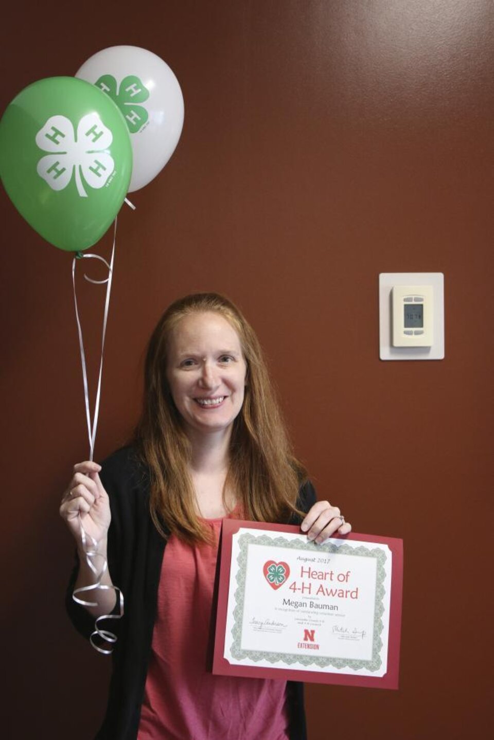 Megan Bauman holding 4-H balloons and a certificate. 