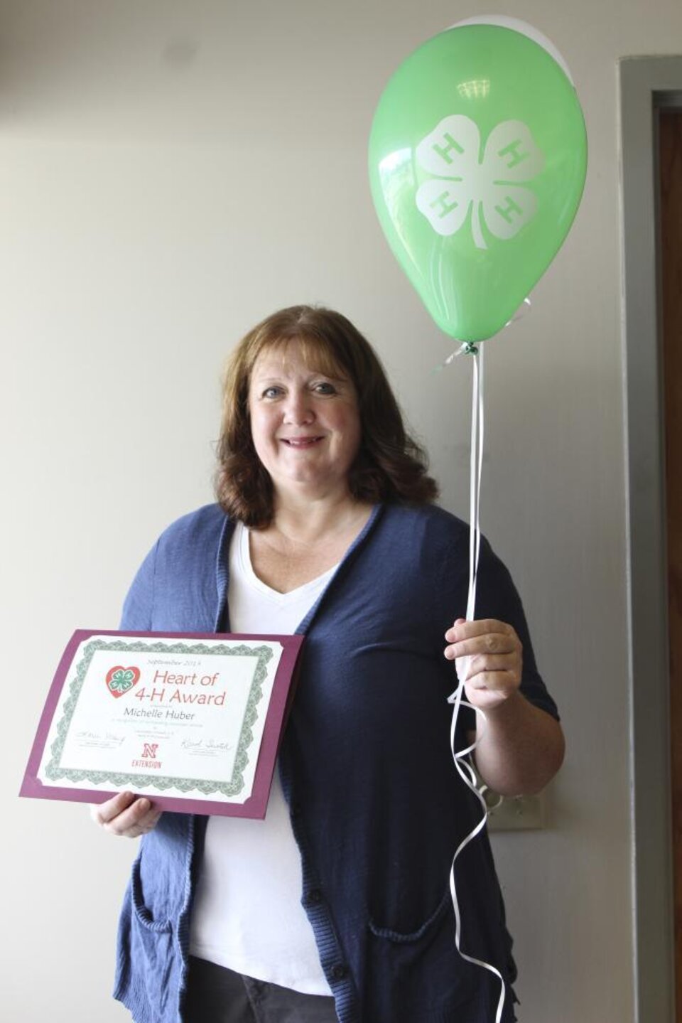 Michelle Huber holding a 4-H balloon and a certificate. 