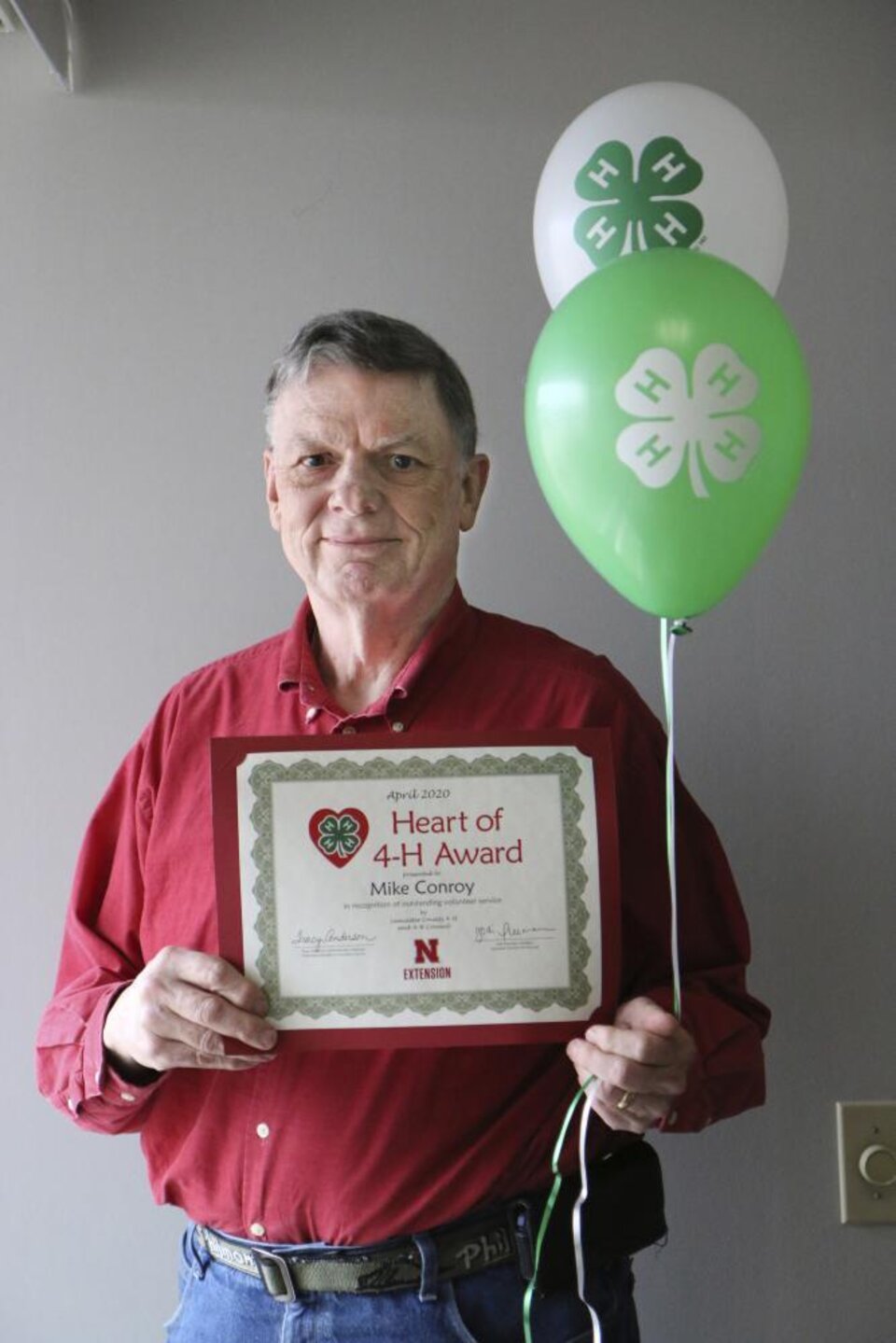 Mike Conroy holding 4-H balloons and a certificate. 