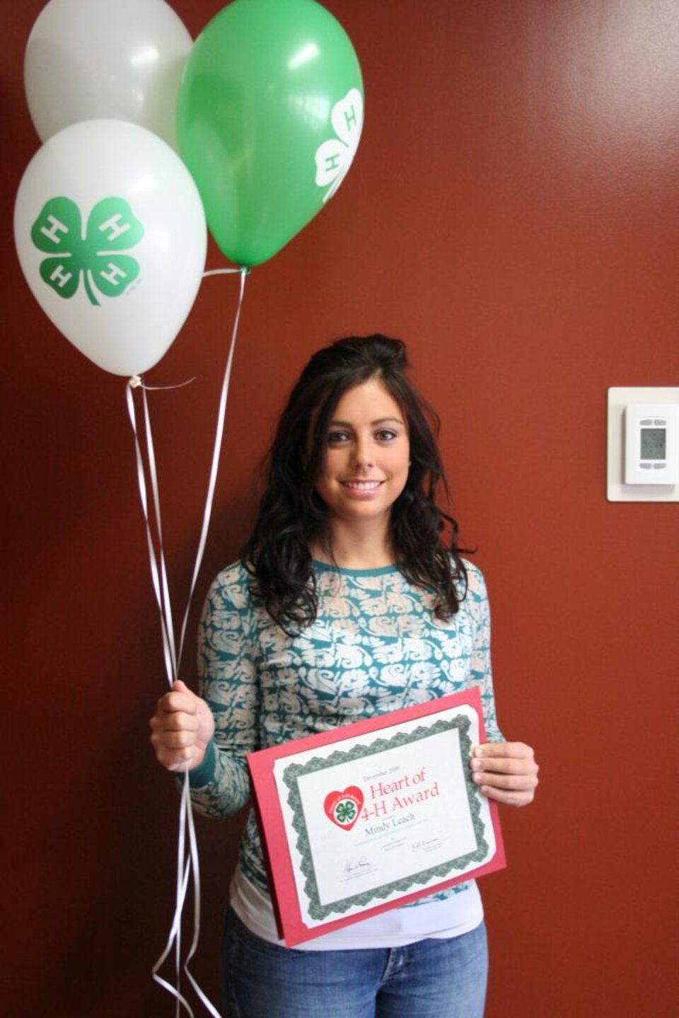 Mindy Leach holding balloons and a certificate 