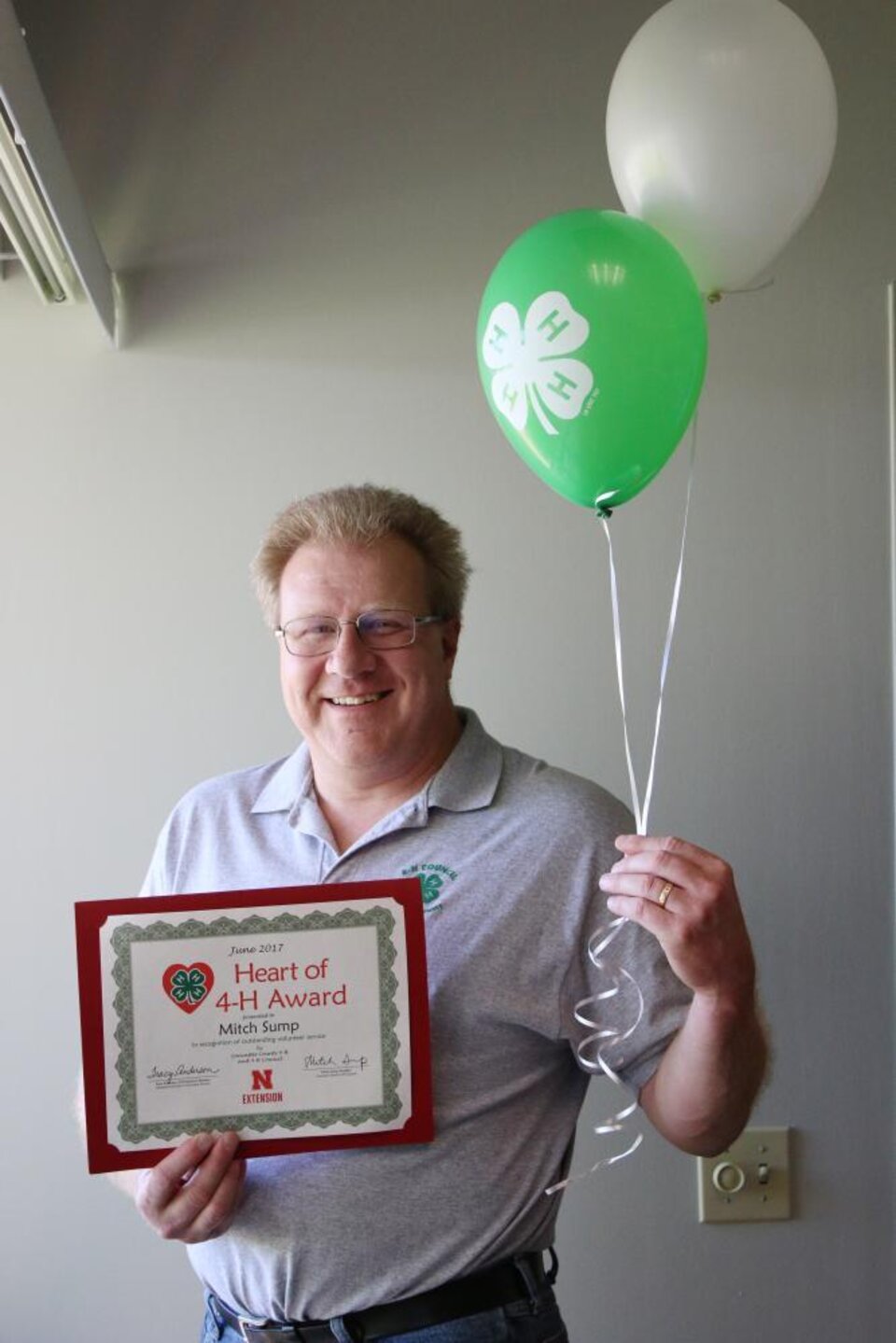 Mitch Sump holding 4-H balloons and a certificate. 