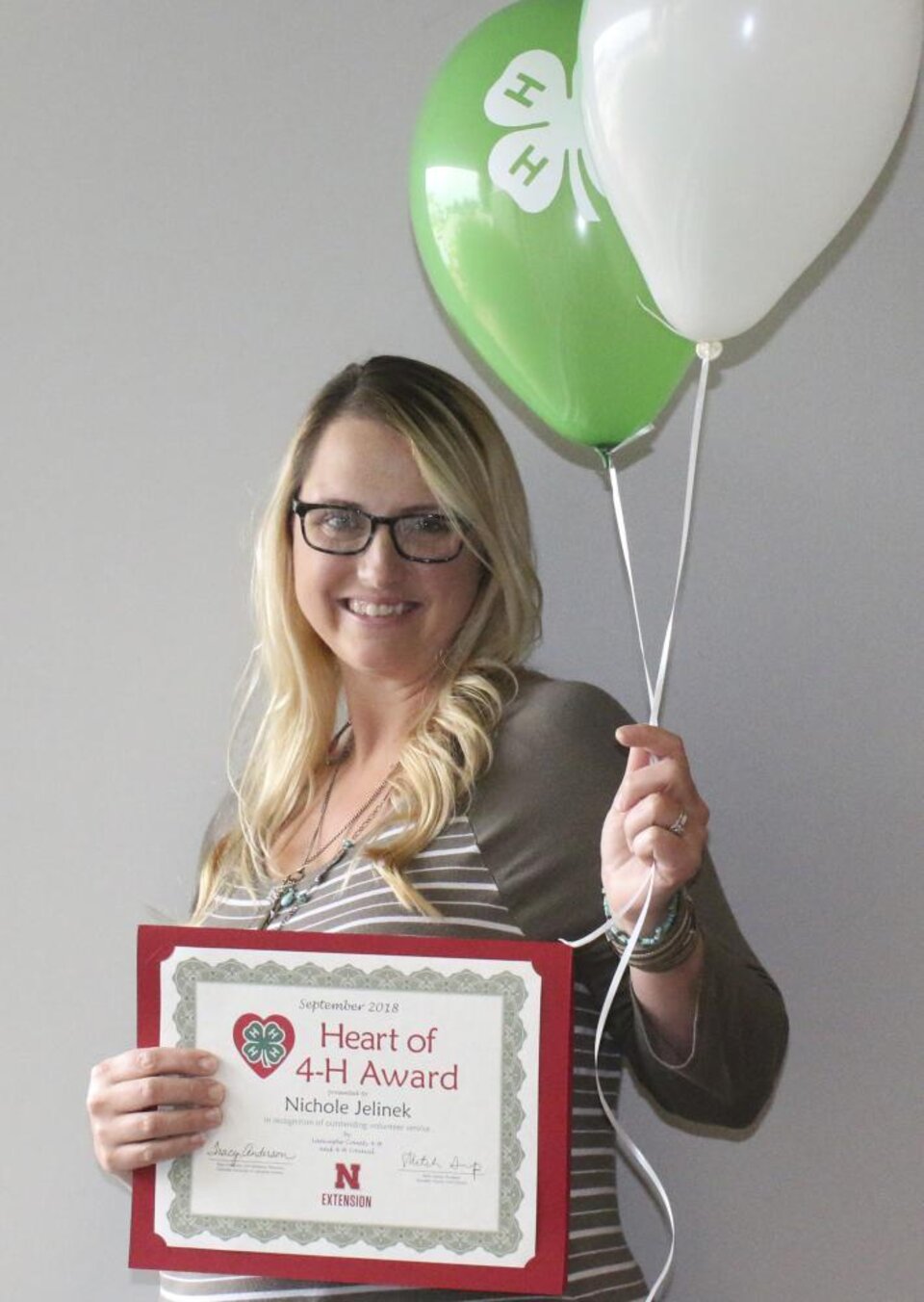 Nichole Jelinek holding 4-H balloons and a certificate. 