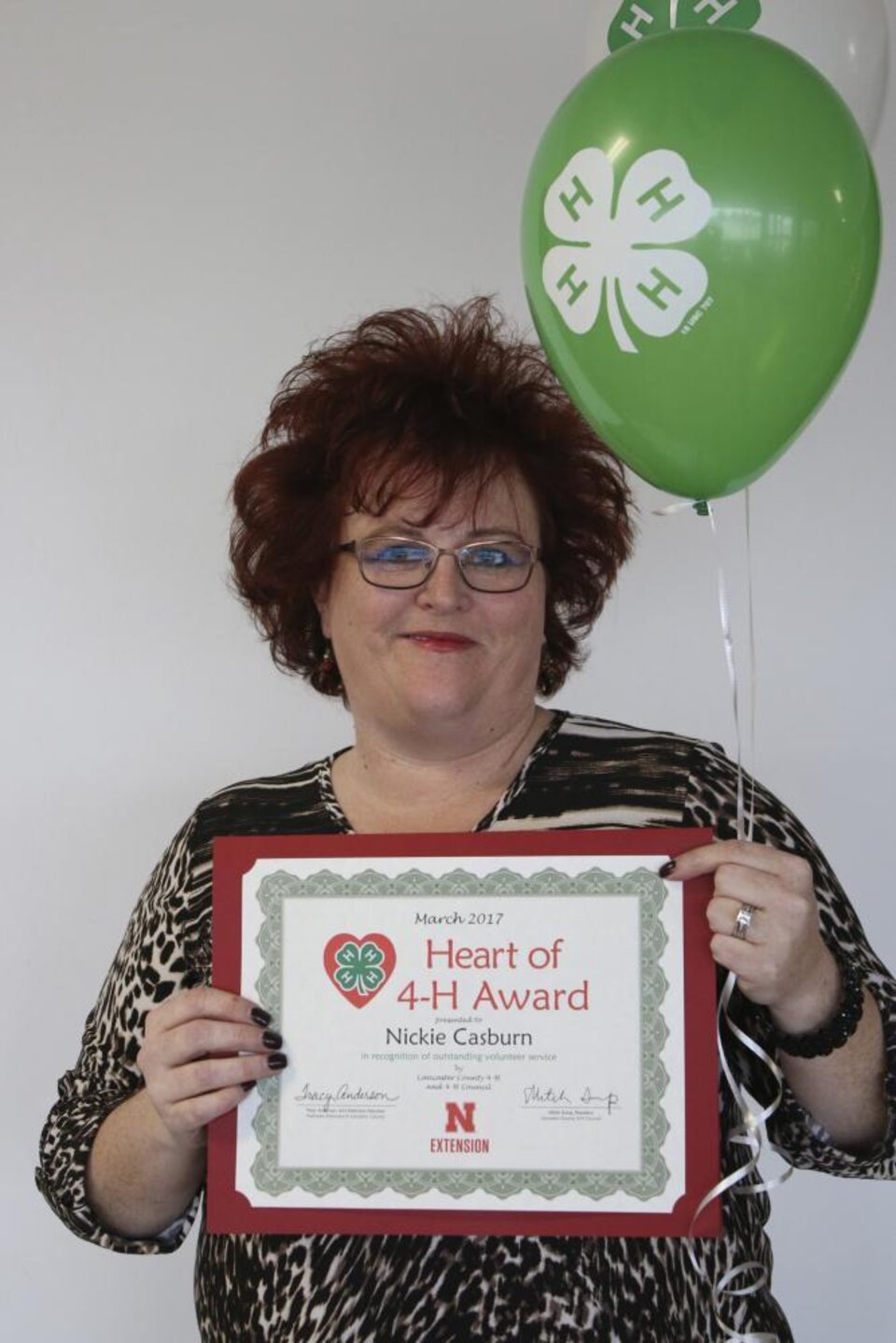 Nickie Casburn holding 4-H balloons and a certificate. 