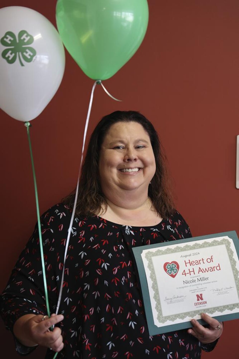 Nicole Miller holding certificate and balloons. 