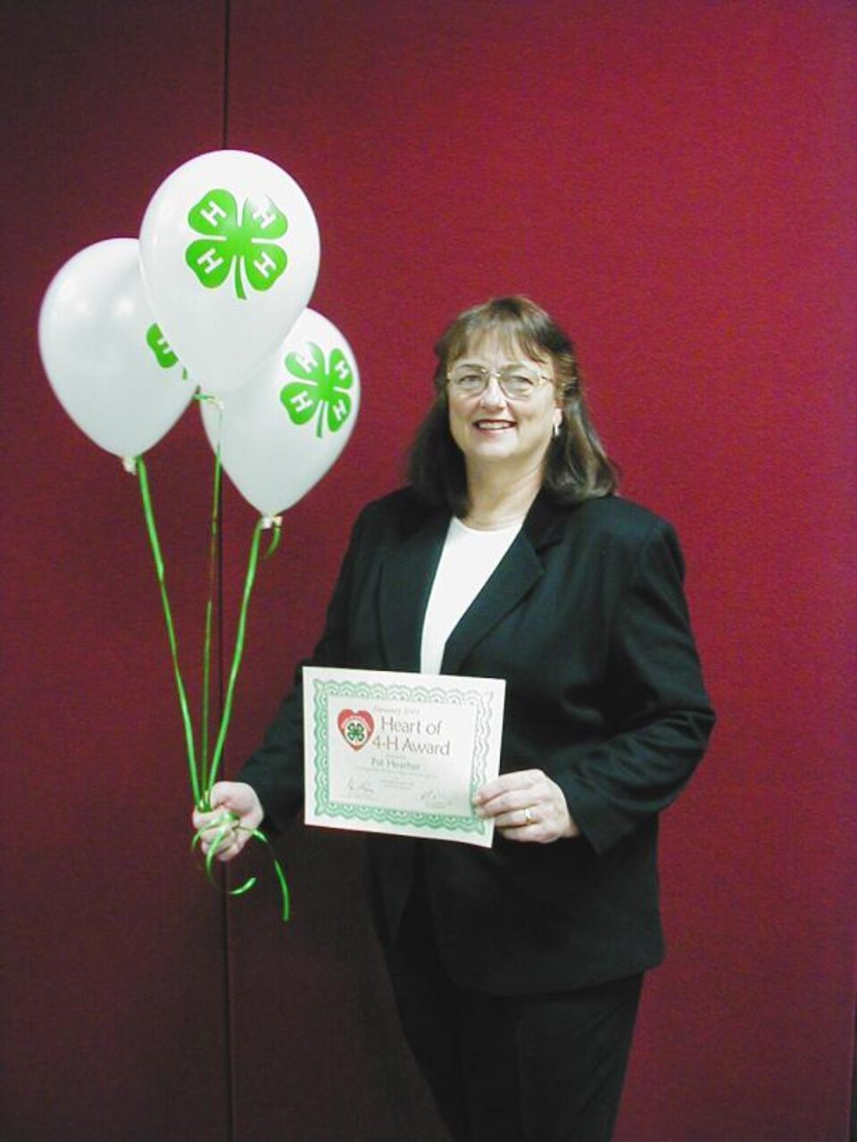 Pat Heather holding certificate and balloons 