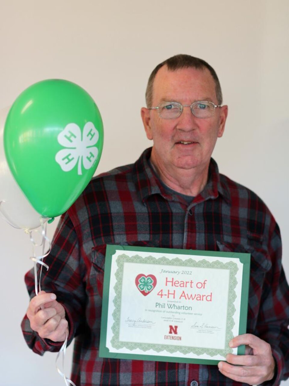 Phil Wharton holding a 4-H balloon and a certificate. 