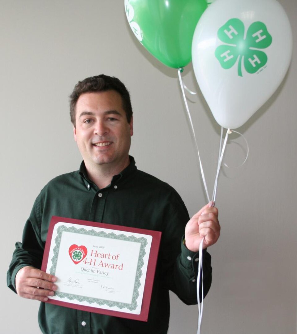 Quentin Farley holding balloons and a certificate 